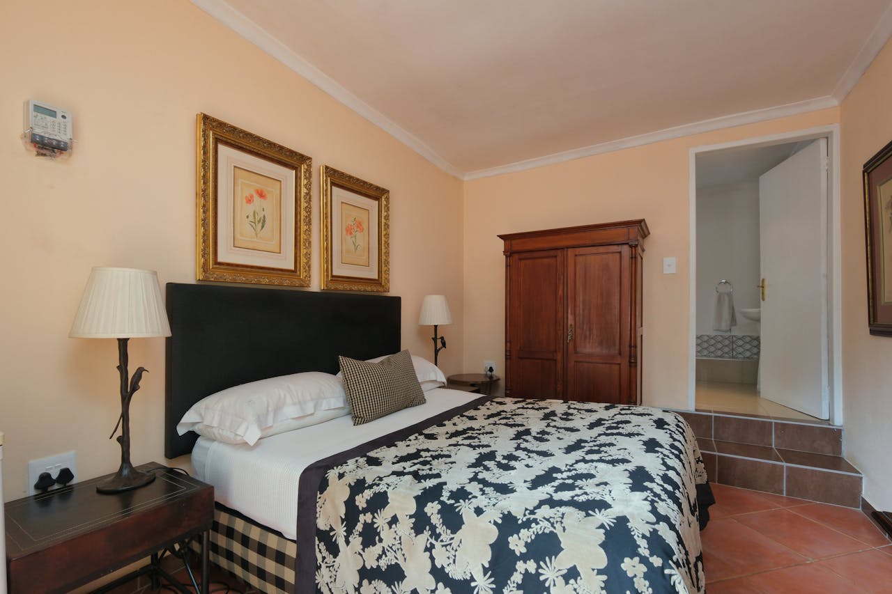 Inviting bedroom with a floral duvet, wooden wardrobe, and elegant decor.